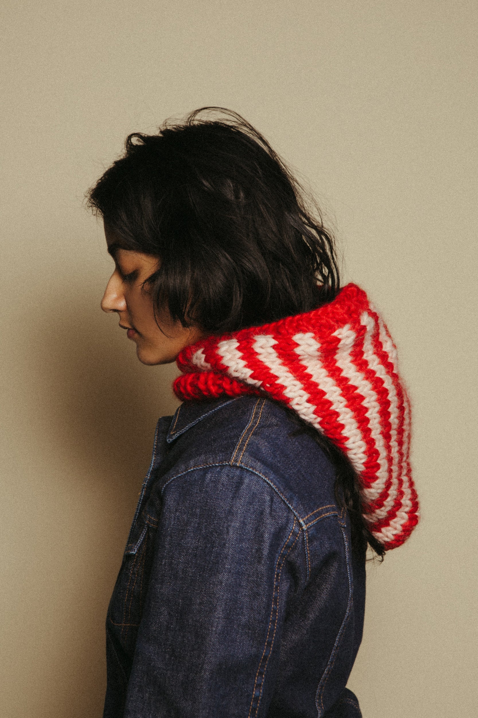 Person wearing a red and white striped hood against a beige background