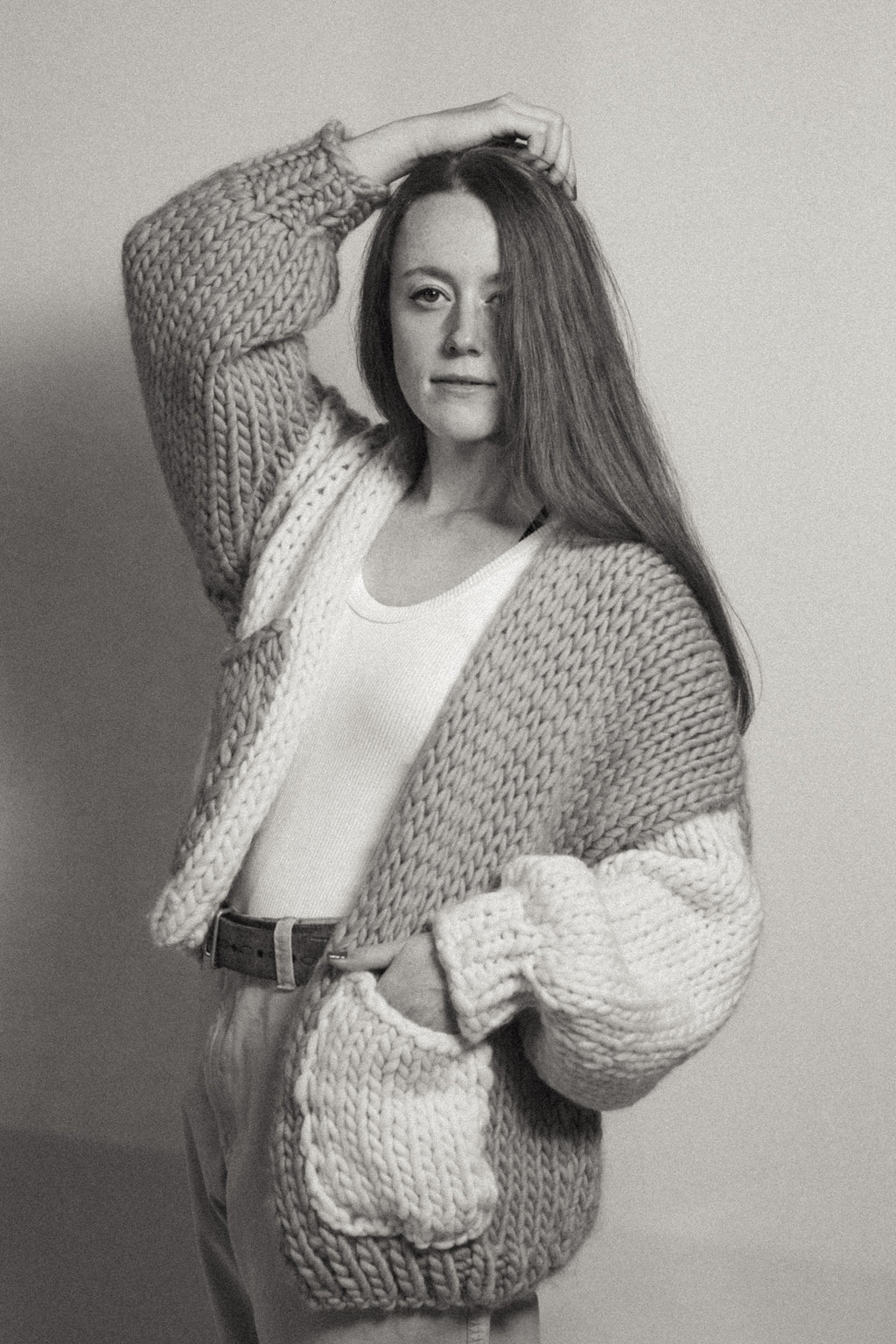 Person wearing a chunky knit cardigan against a plain background