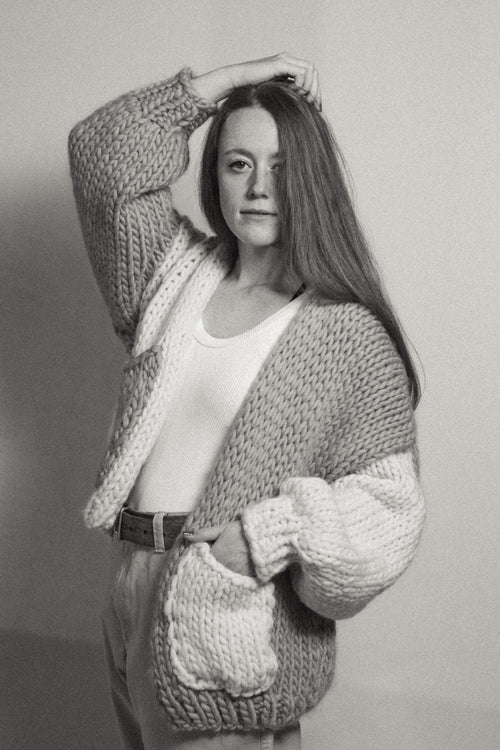 Person wearing a chunky knit cardigan against a plain background