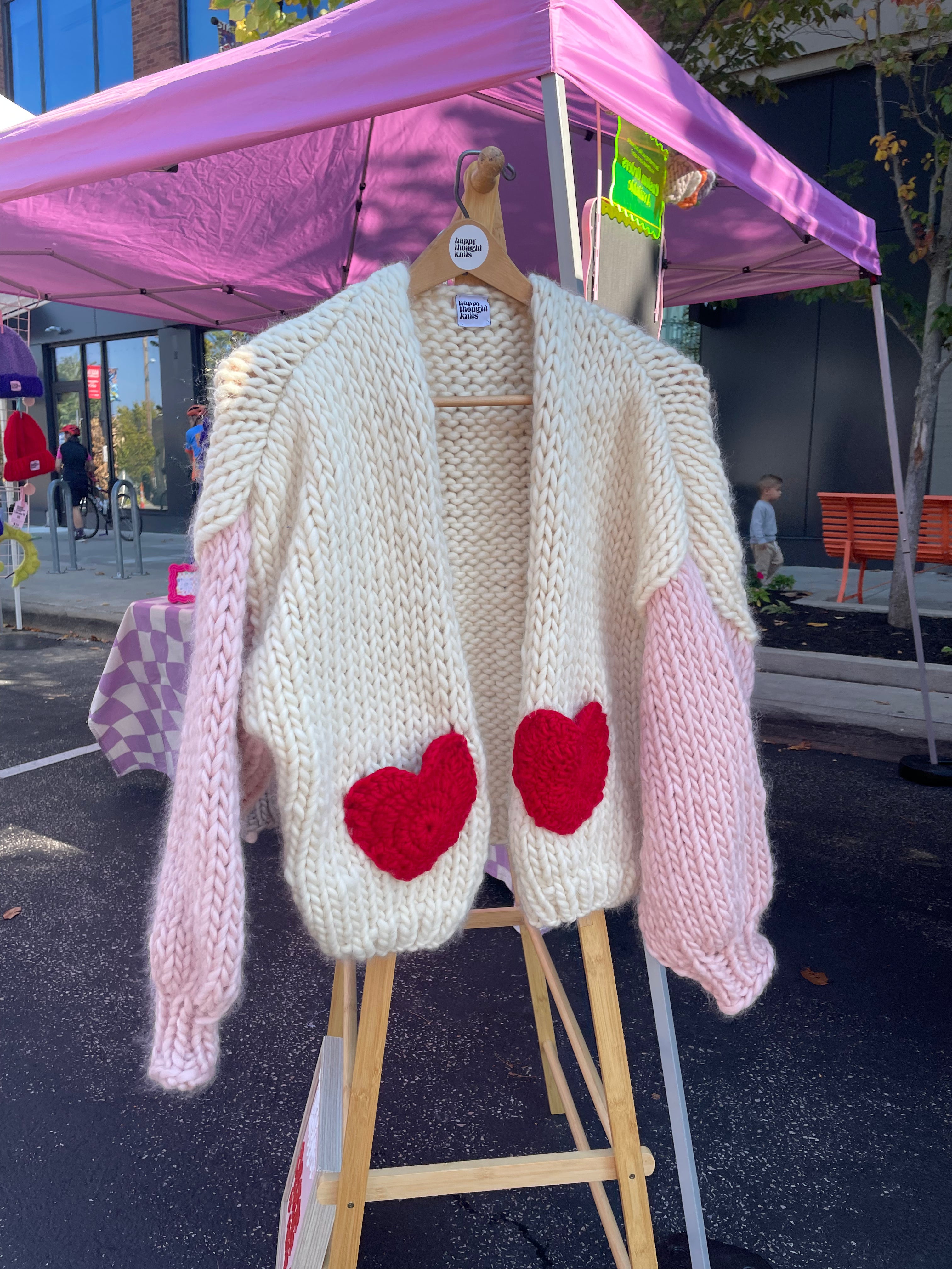 Knitted cardigan with red heart pockets on a stand outdoors
